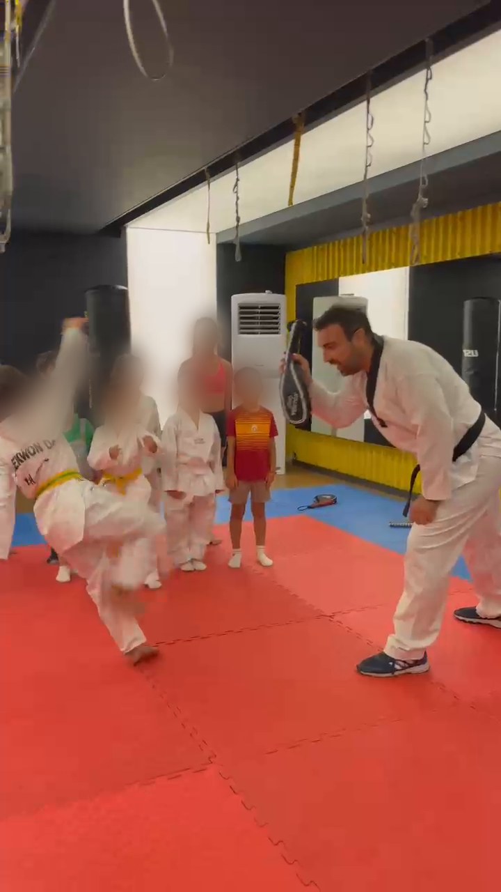 Osman Akınay çocuk Taekwondo dersinde pad tutarken